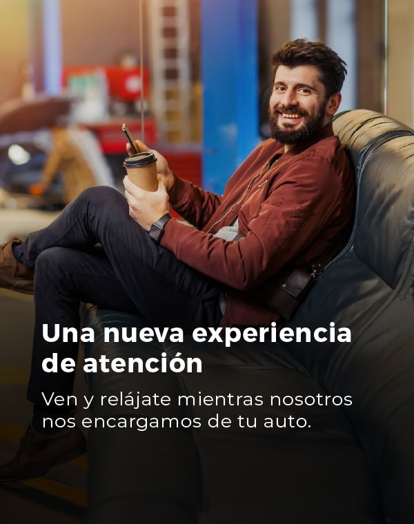 Hombre sonriente en sala de espera de Salfa Sur Automotriz con café.