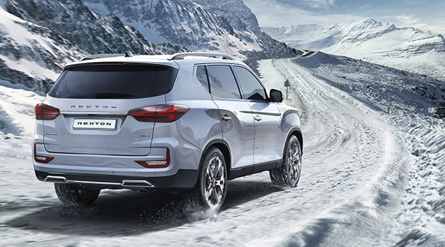 Vehículo SUV en paisaje nevado con montañas y caminos helados.