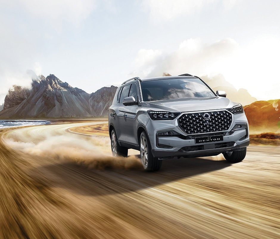Vehículo SUV en movimiento en un paisaje montañoso y desértico.