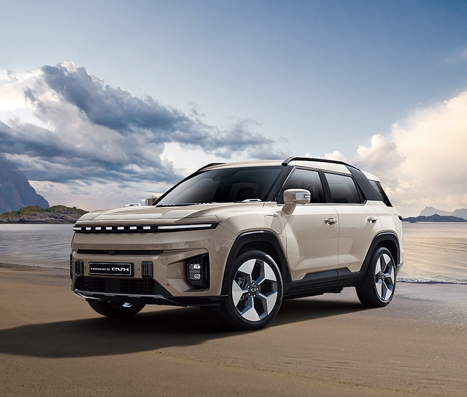 Crossover SUV en playa con paisaje de montañas y cielo nublado.