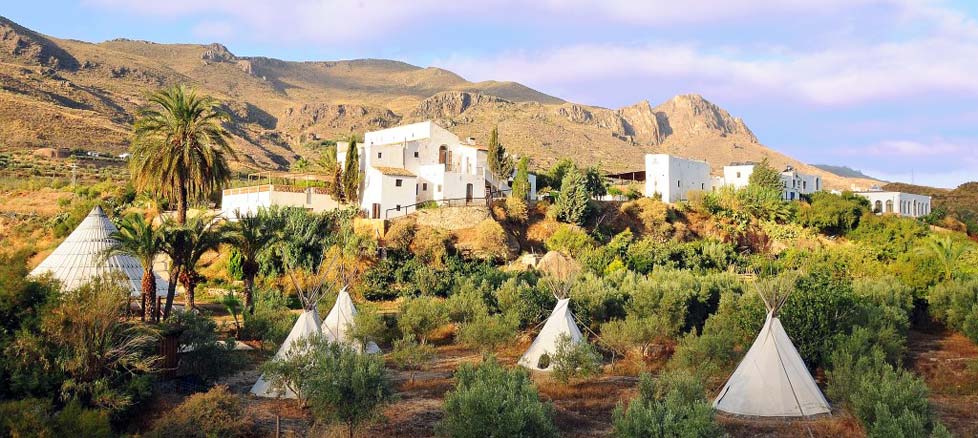 Global Ecovillage Network community with white buildings and tents in arid landscape.