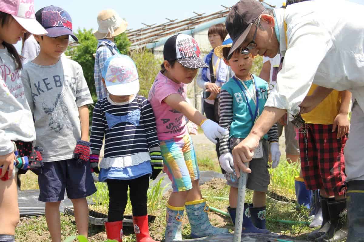 Children participating in outdoor gardening activity at Ecovillage Network event.