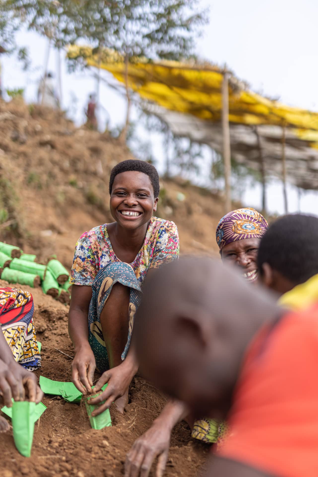 Smiling community members planting saplings together at a hillside garden.