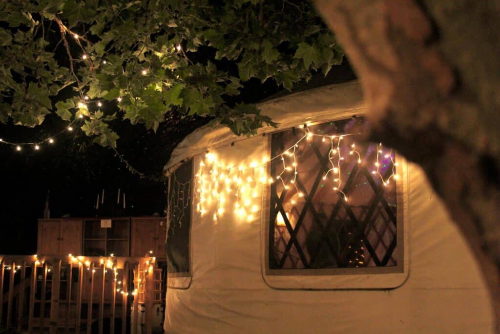 Night scene with string lights on a caravan at an eco village.
