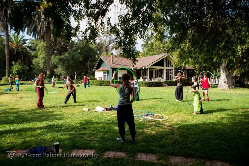 People in a park practicing hula hoop and group activities at an eco village.