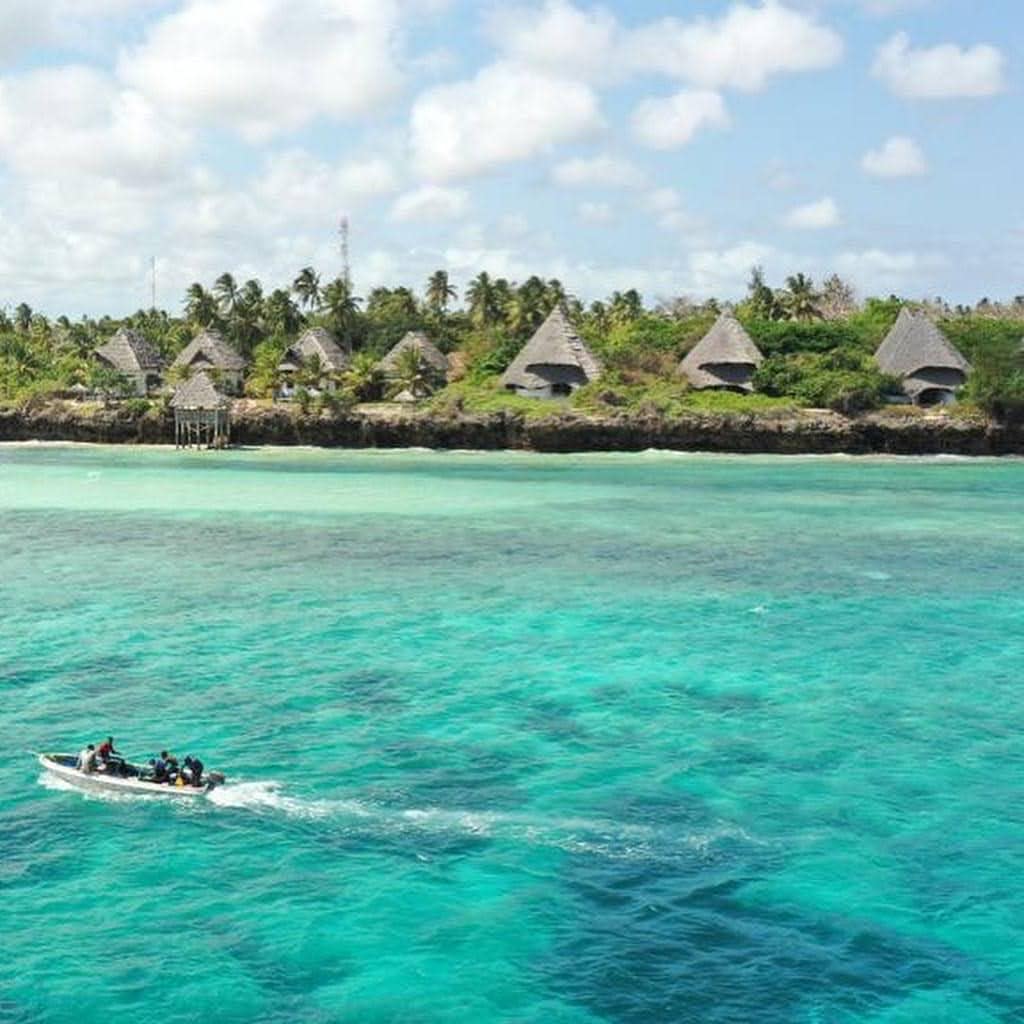 Overwater turquoise sea with thatched huts on a tropical island.