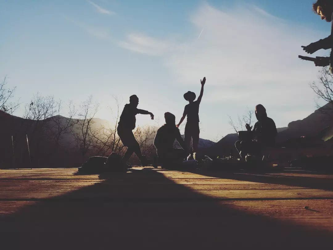 Group of people dancing and celebrating at sunset in an outdoor setting.