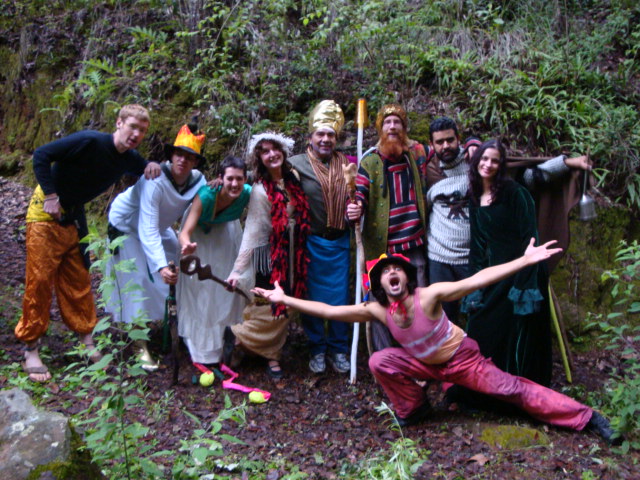 Group of people in costumes posing outdoors with greenery.