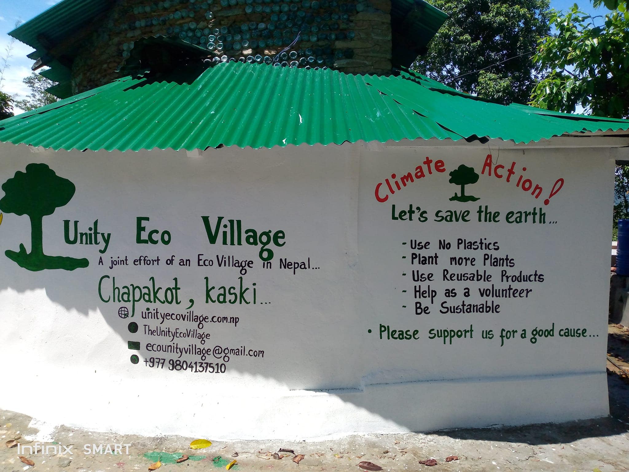 Unity Eco Village sign with climate action message and greenery.