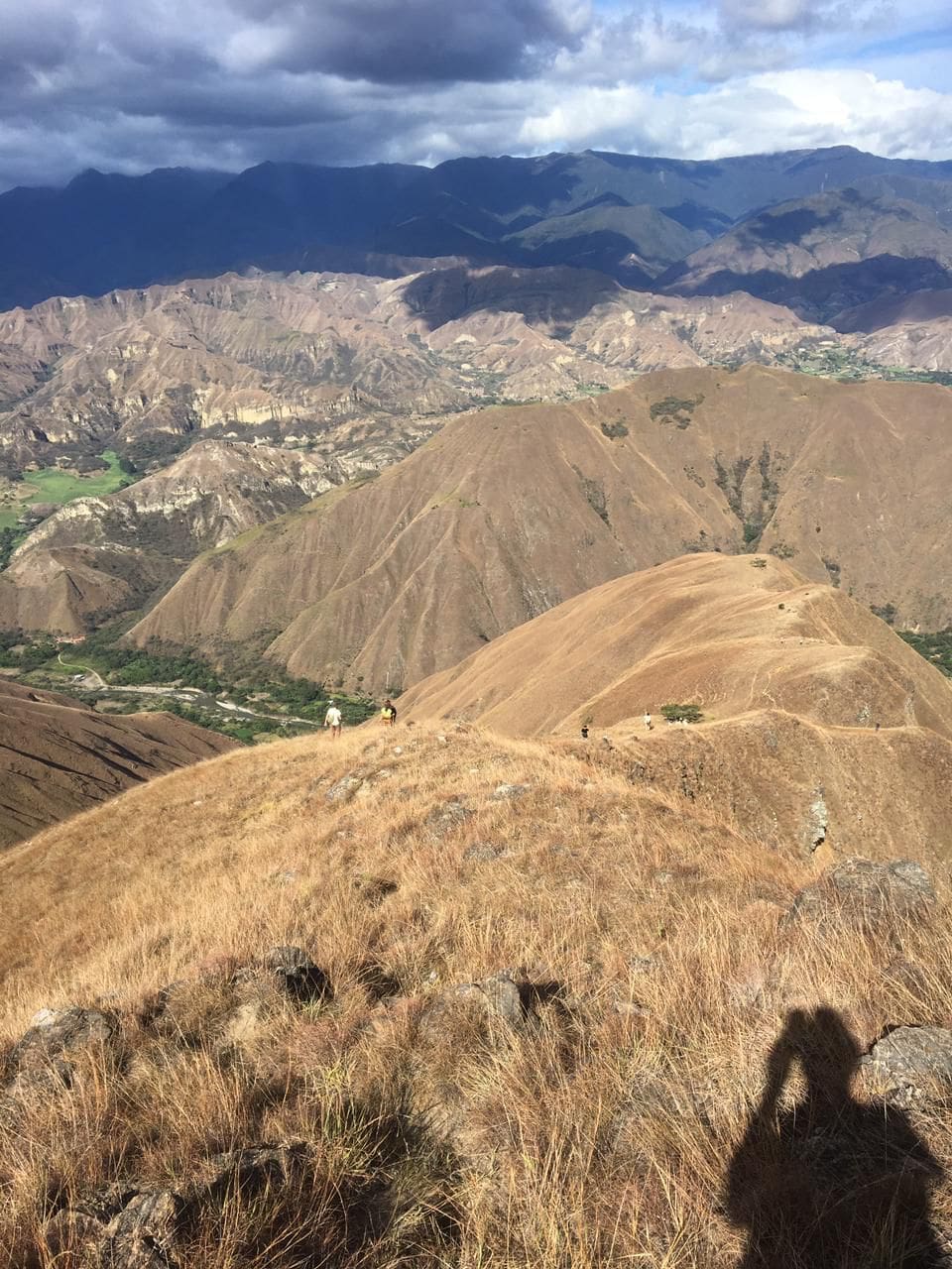 A sweeping landscape of brown hills and distant mountains under a partly cloudy sky.