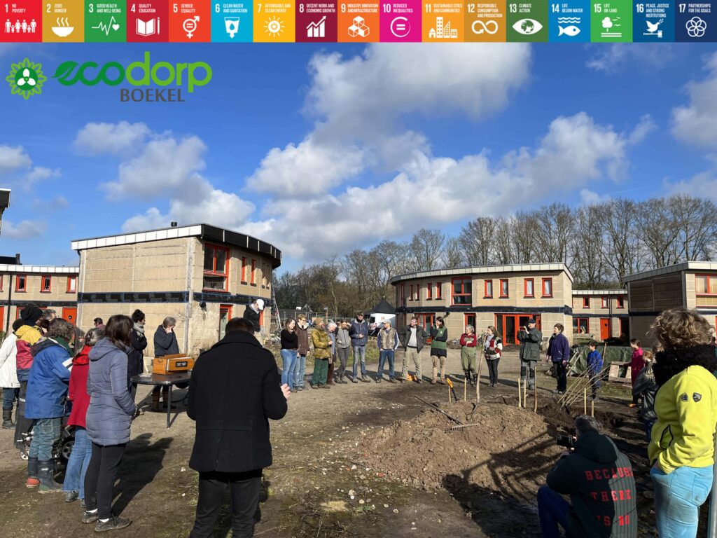 People gathered in a U-shaped circle at Boekel Ecovillage during a community event.