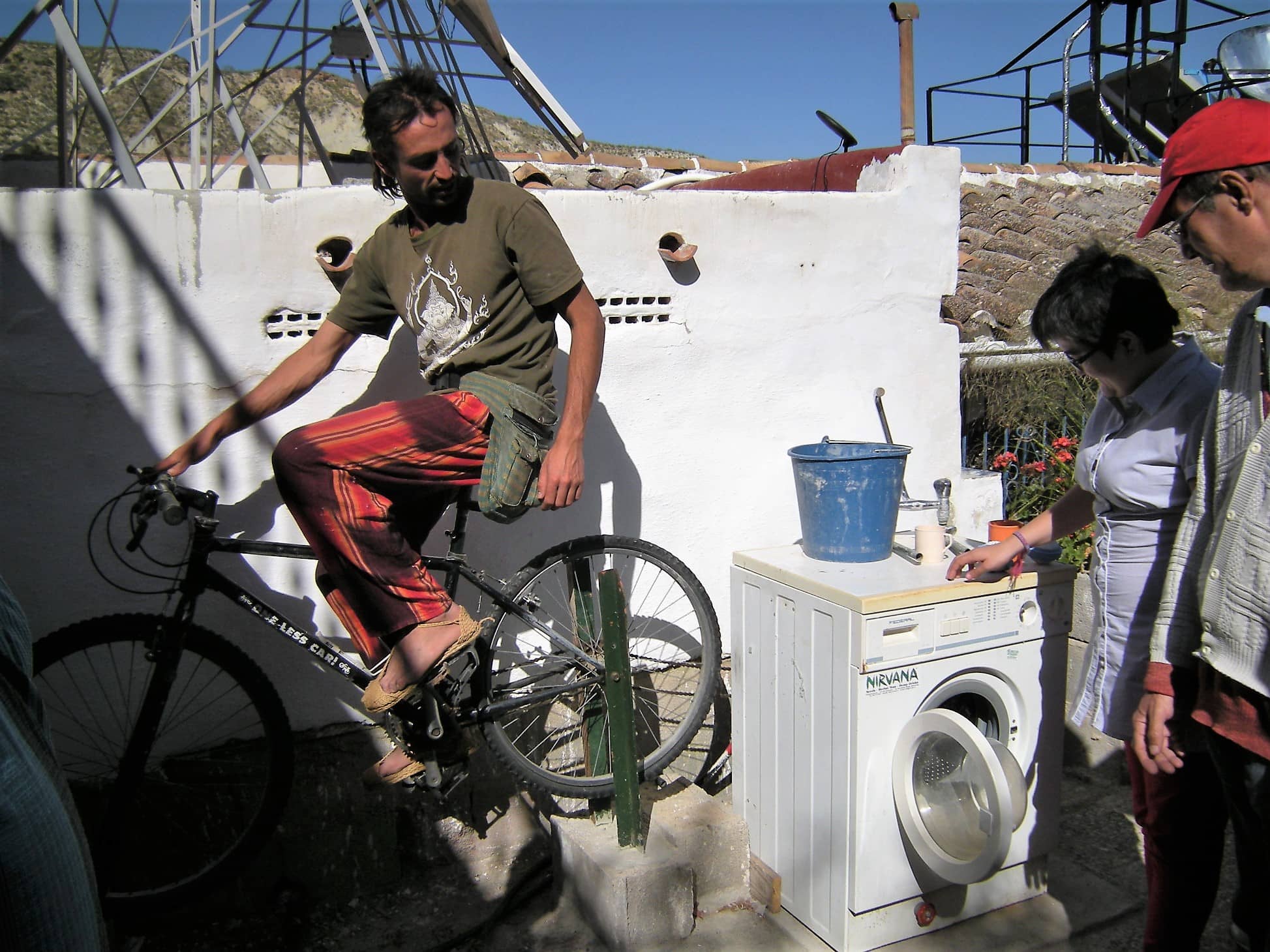 Man on a bicycle near a washing machine and wash area at an eco community.