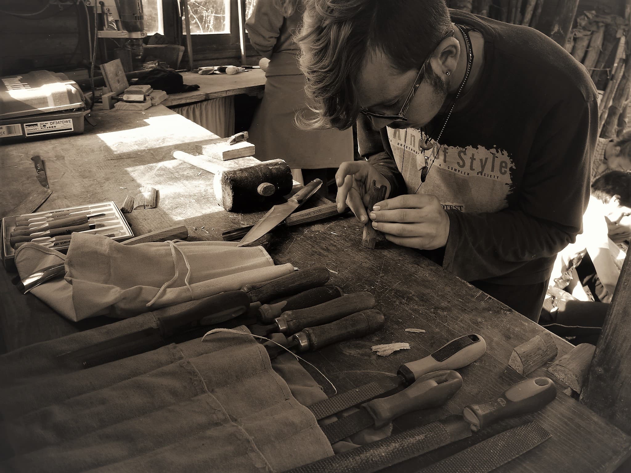 Craftsperson engraving a piece at a woodworking bench in a workshop.