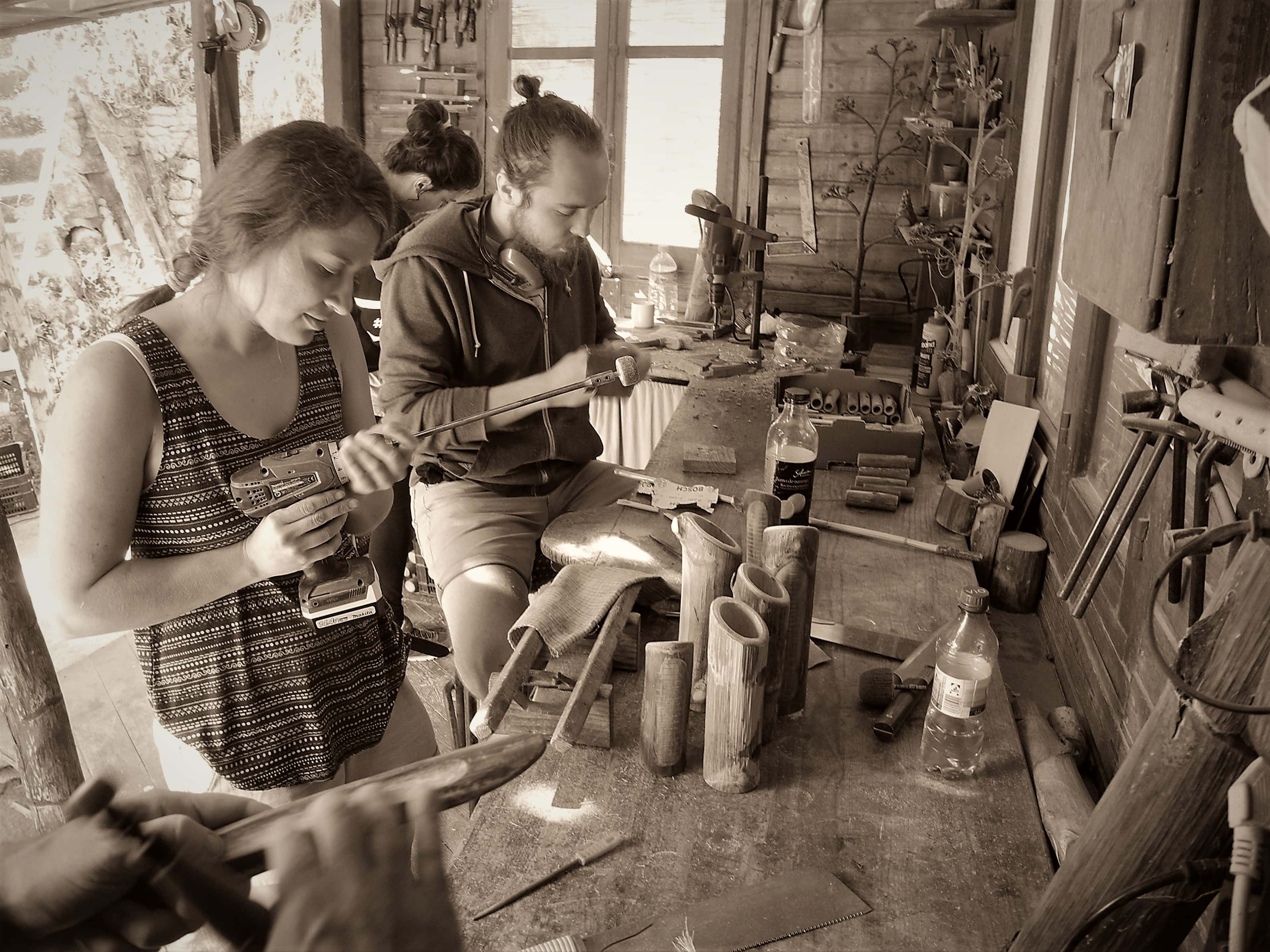 People crafting metal and wood objects in a rustic workshop at EcoVillage.