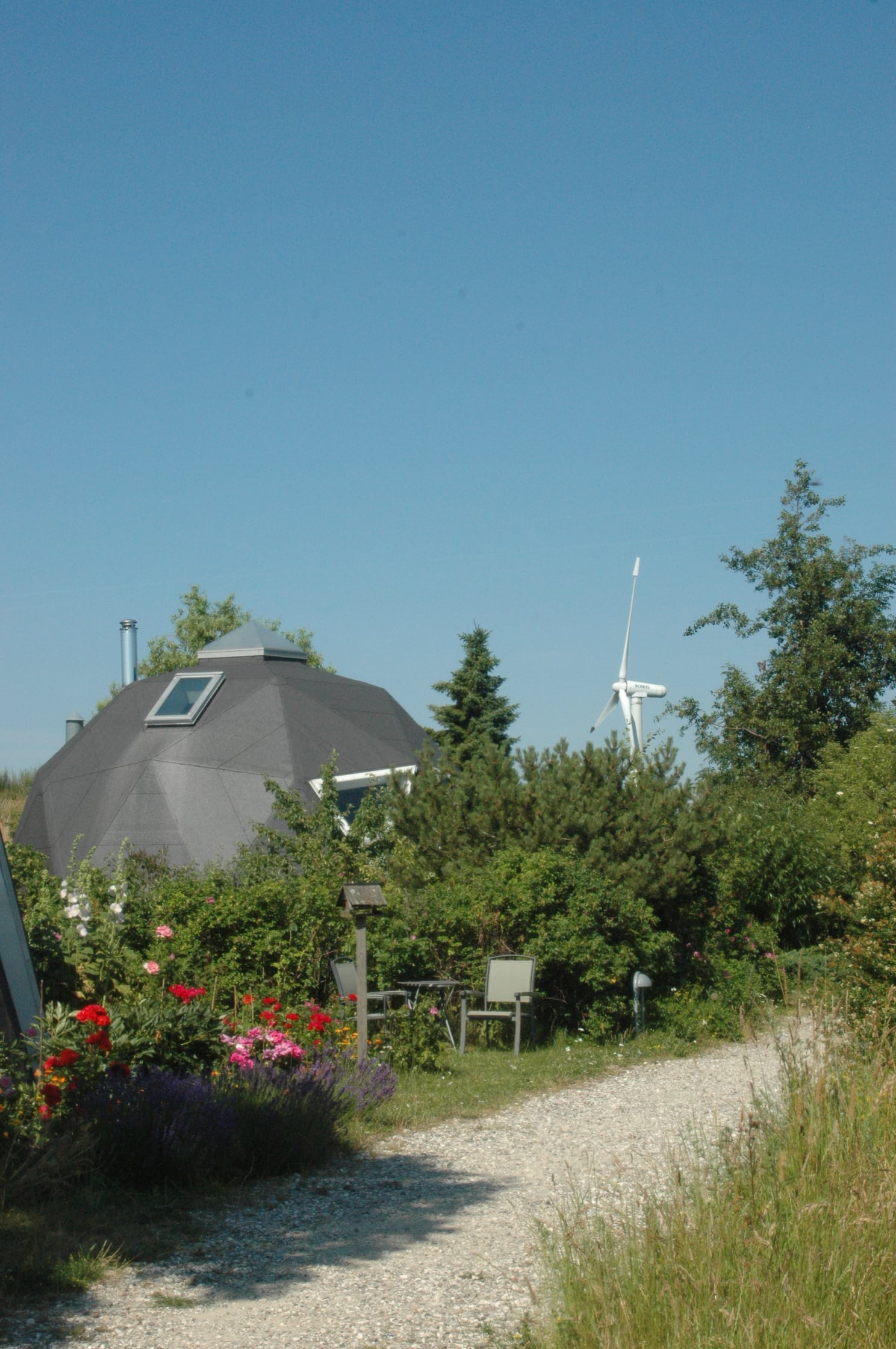 Dyssekilde eco-community with geodesic dome, wind turbine and garden path.