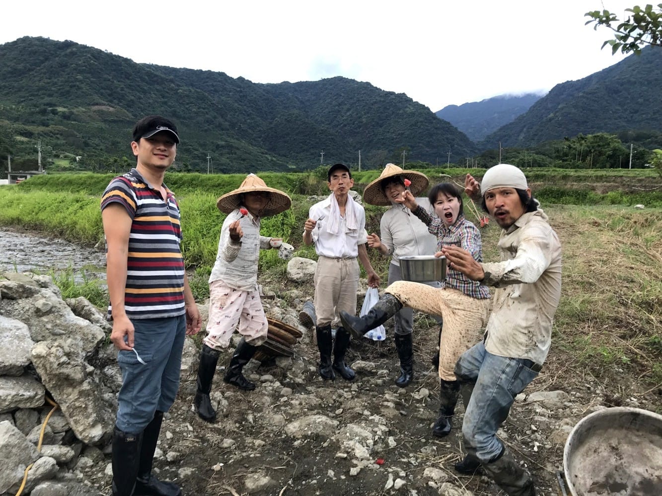 Group of people in rural fields with mountains in the background.