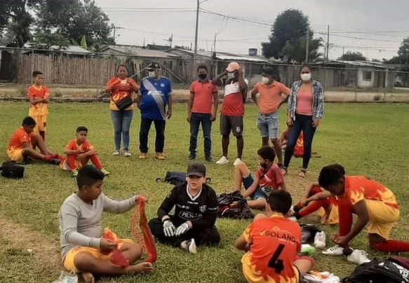 Group of children and adults on a field preparing sports gear.