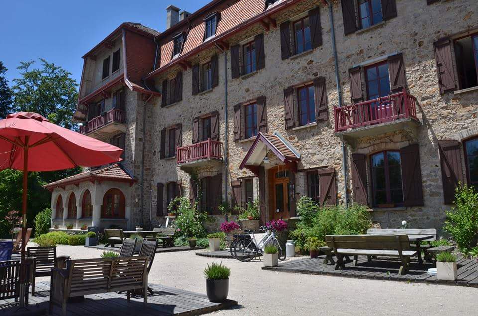 Global Ecovillage Network inspired stone building with outdoor seating and garden.