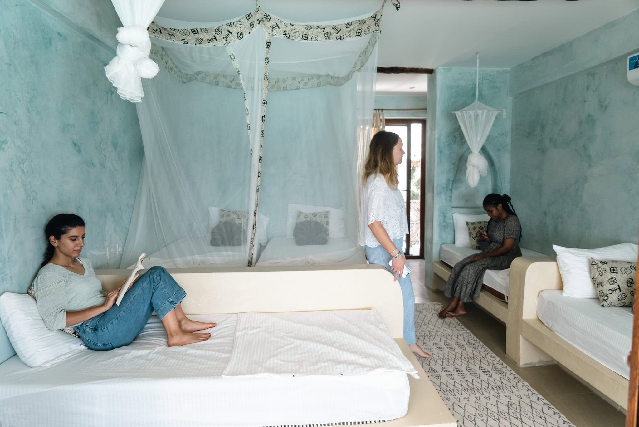 Teenager and adults in a tropical eco-village bedroom with canopies.