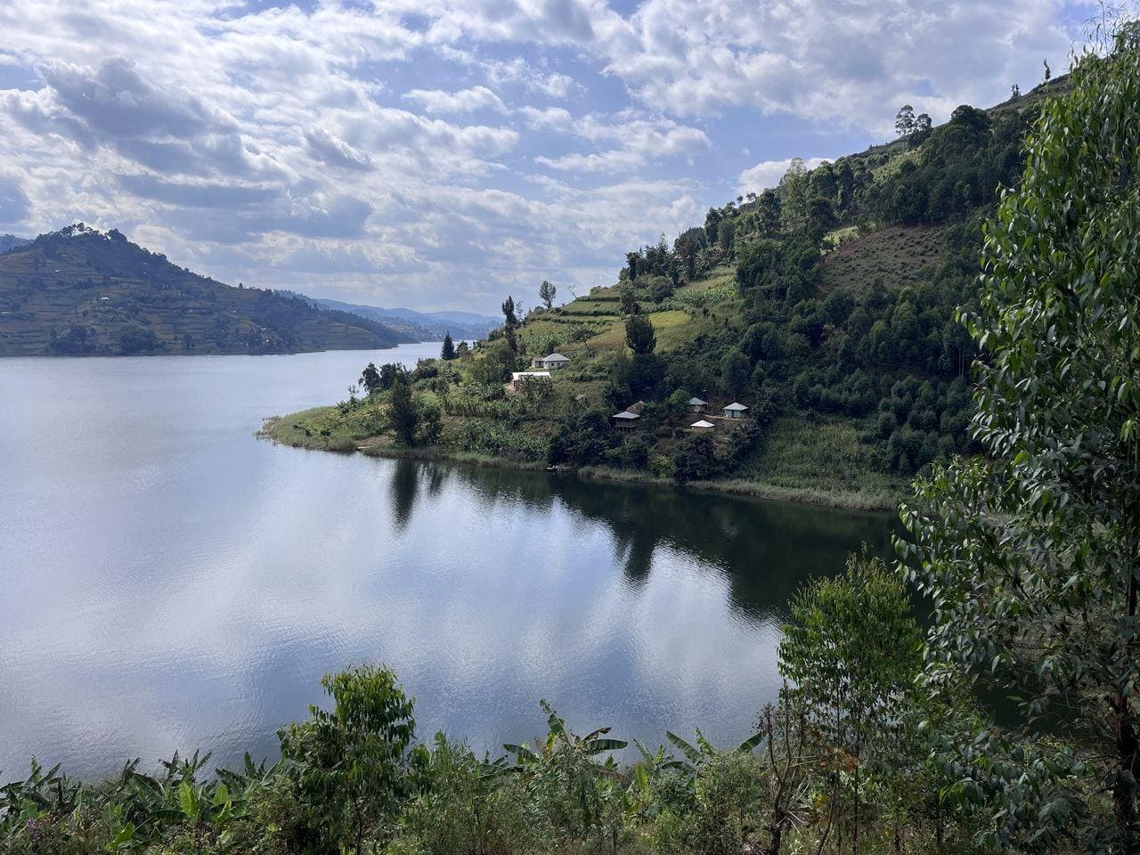 Scenic hillside village by Lake Bunyonyi with terraced farms and green vegetation.