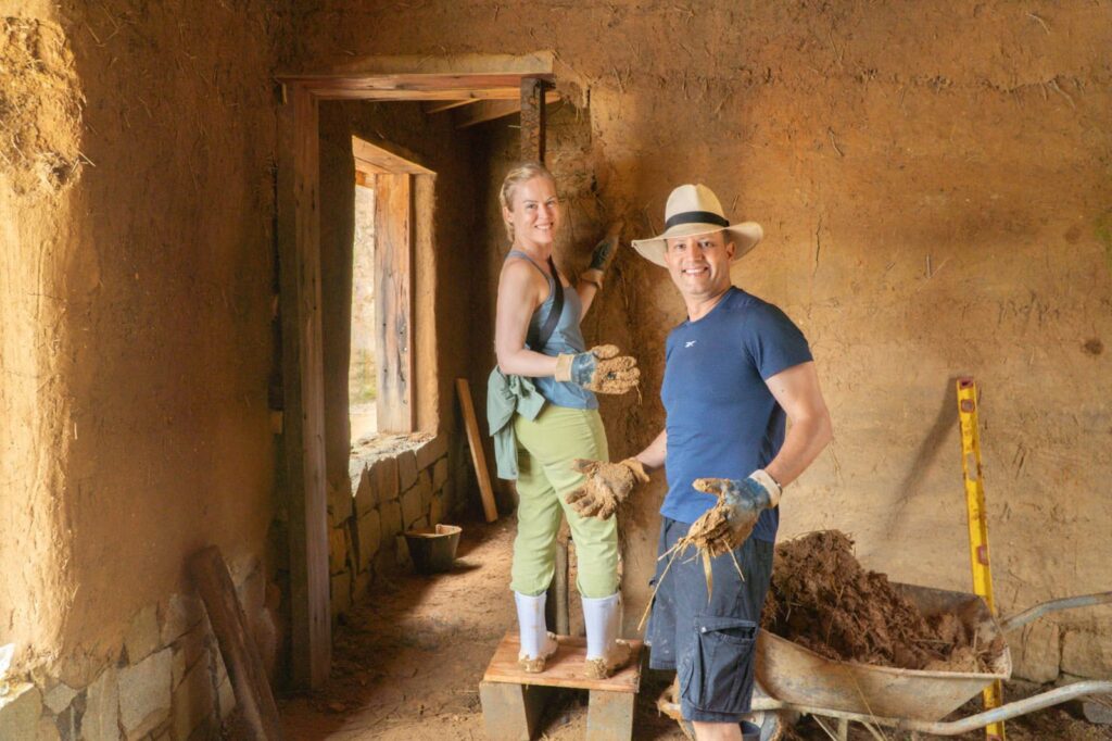 Volunteers building a straw bale house inside rustic eco home.