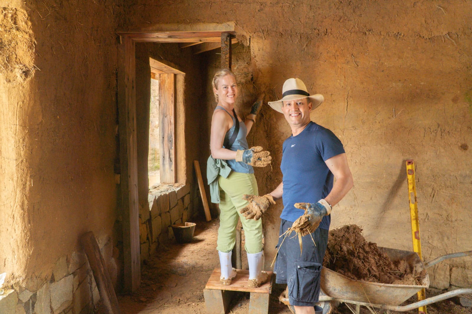 Volunteers building a straw bale house inside rustic eco home.