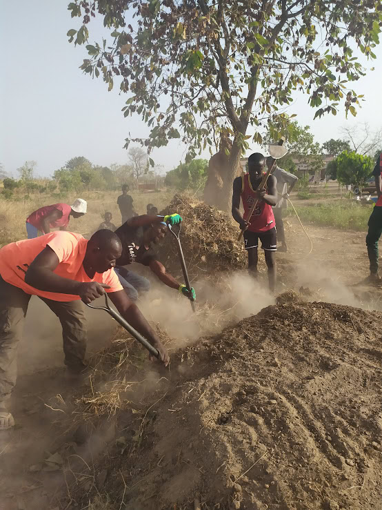 Group of volunteers working together on a dusty hillside at a community farm.