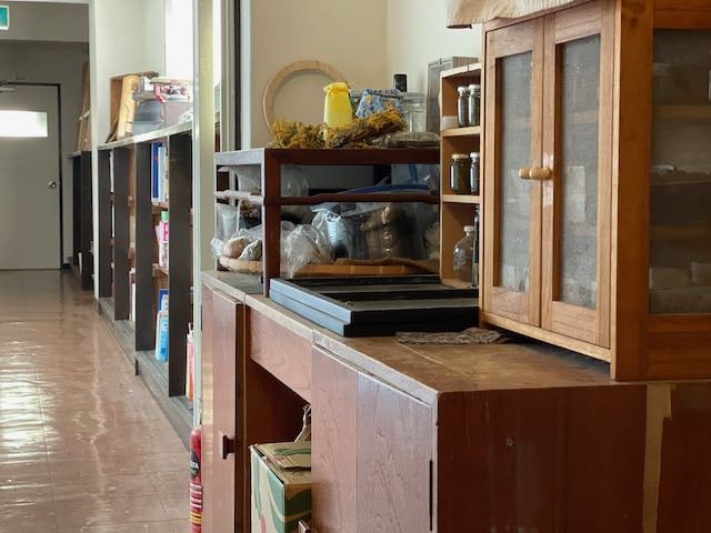 Interior view of a classroom or community space with shelves and wooden cabinets.