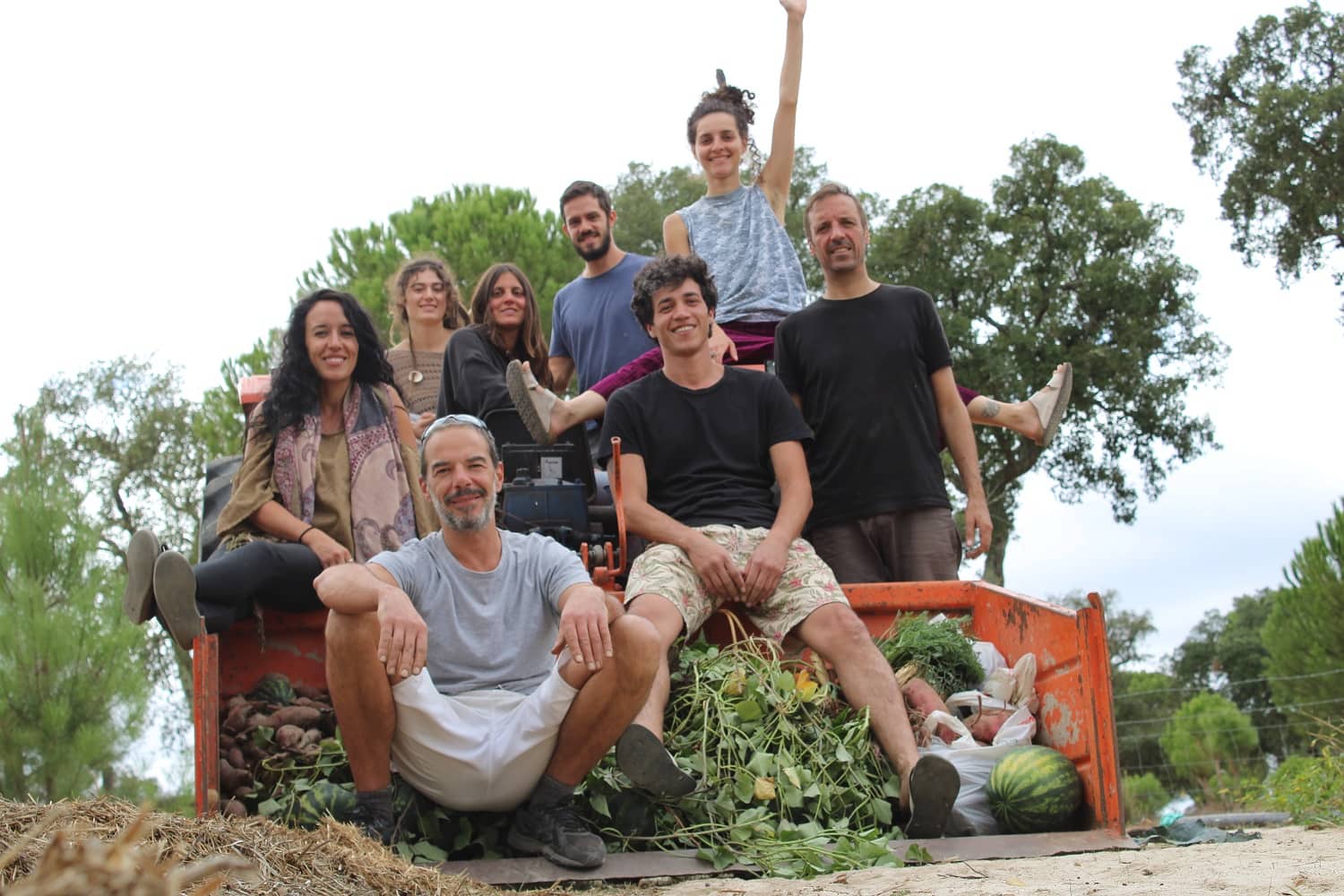 Group of diverse people posing on a harvest truck with produce.