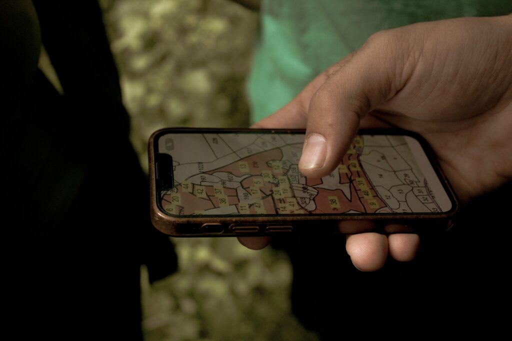 Hand holding smartphone displaying Global Ecovillage Network map.
