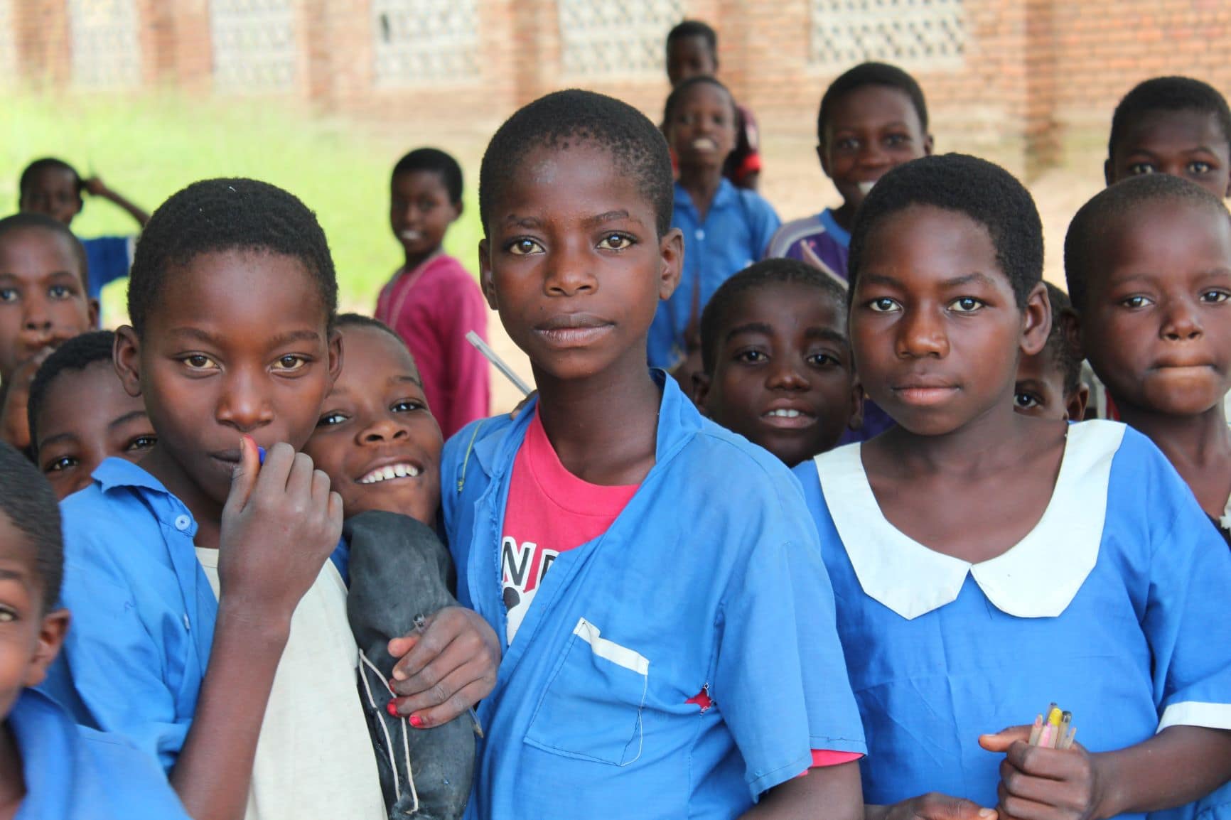 Group of diverse schoolchildren in blue uniforms posing for a photo.