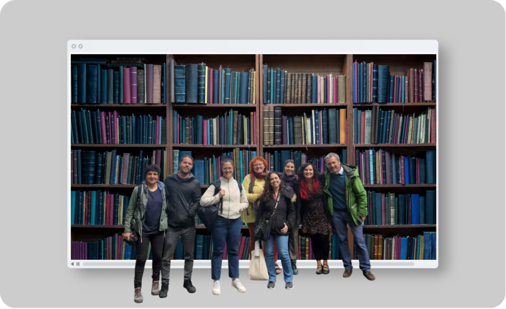 Group of people standing in front of a large bookshelf with colorful books.