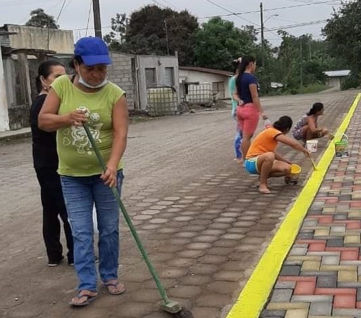 Community volunteers constructing a colorful brick sidewalk with a yellow curb.
