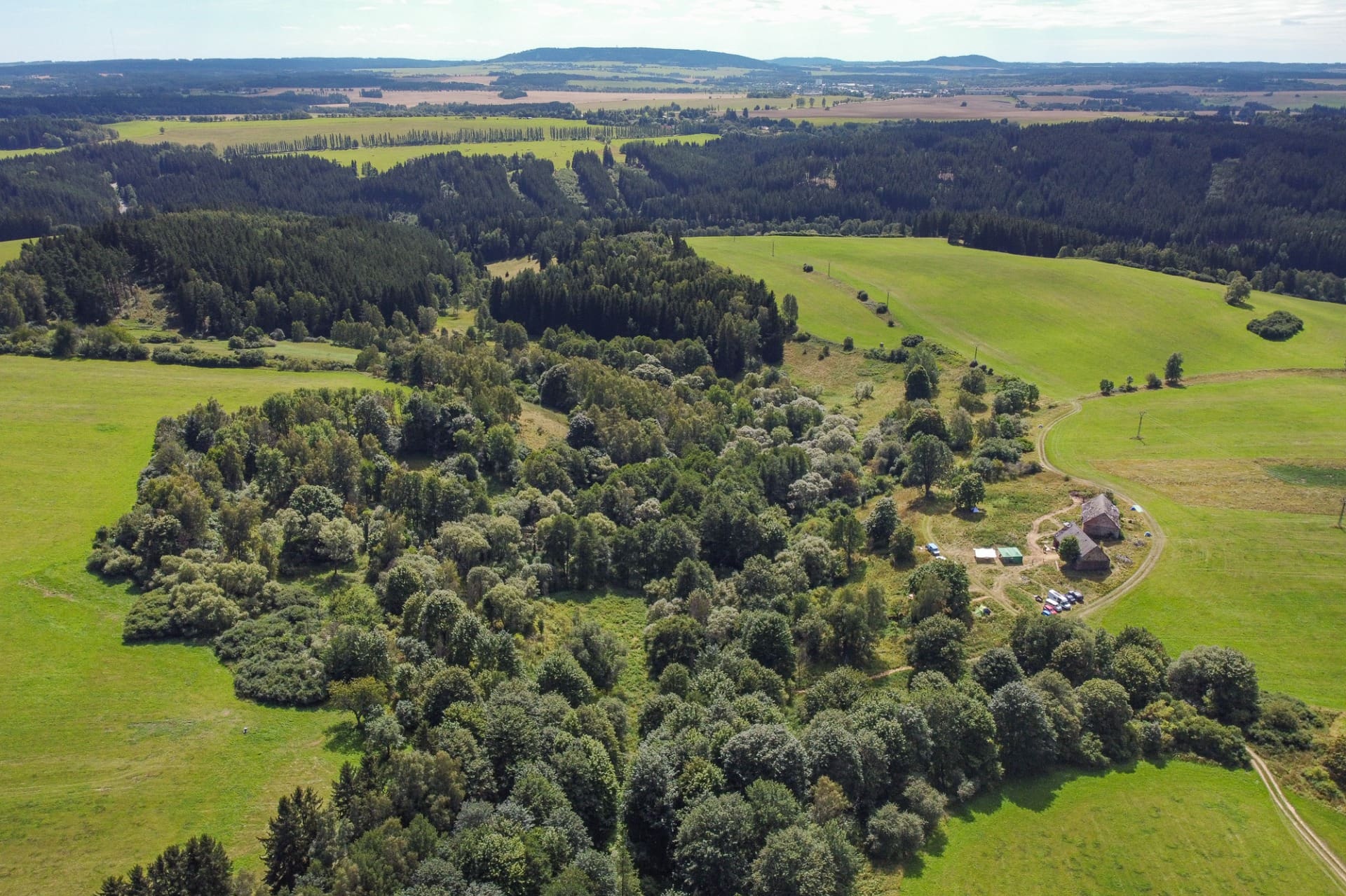 Aerial view of a rural eco-village with houses, fields and surrounding forest.