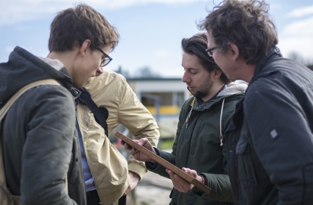 Group of people discussing with a clipboard at an ecovillage site.