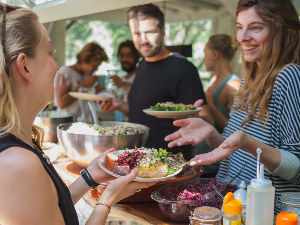 Group of people sharing a vibrant communal meal at an outdoor eco village event.