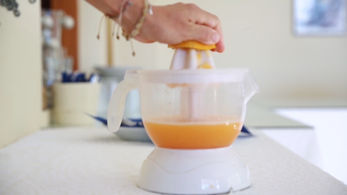 Person pressing a citrus juicer to extract juice.