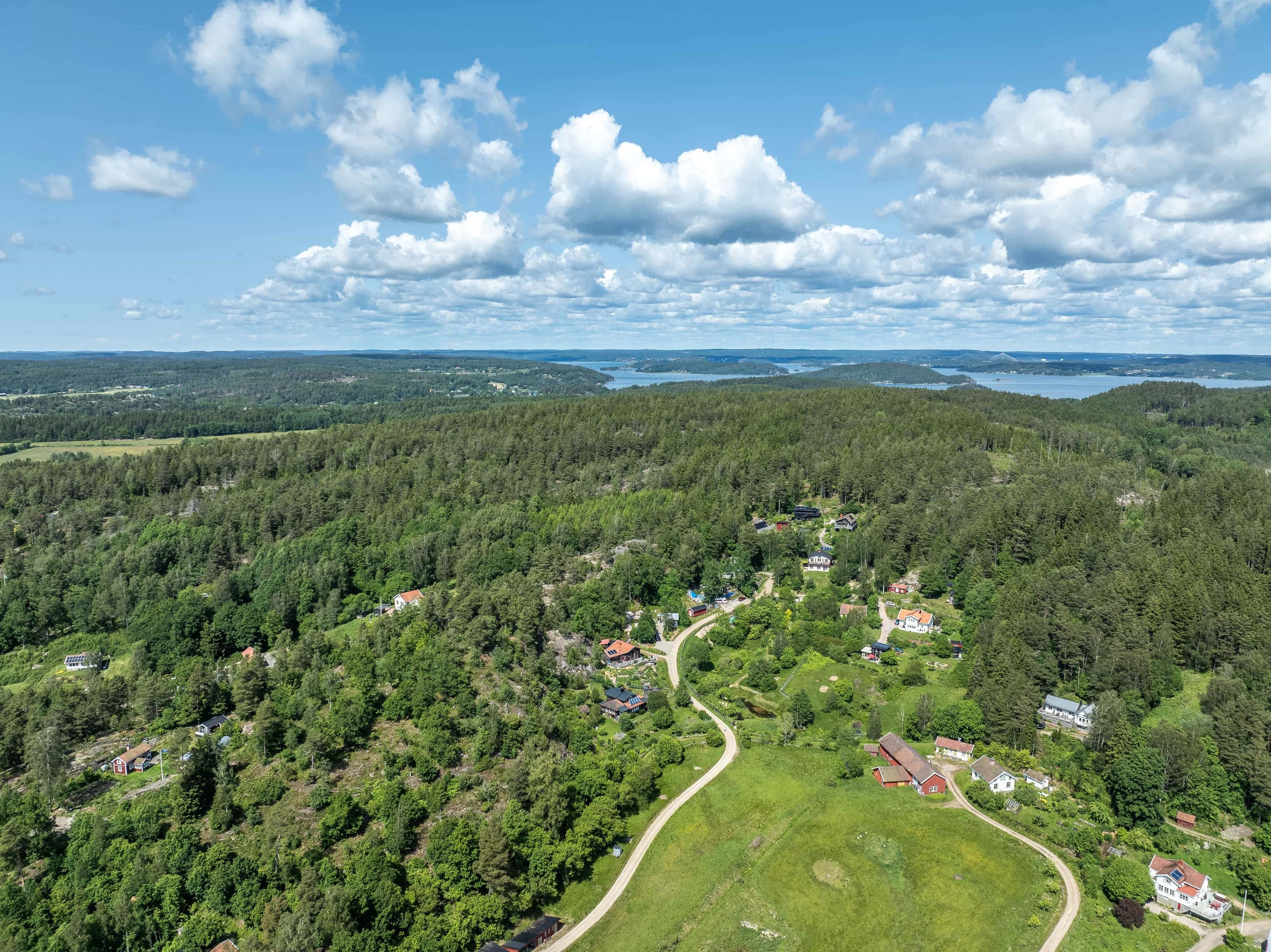 Aerial view of dense forest, winding roads, and scattered houses at Utsikten Ecovillage.