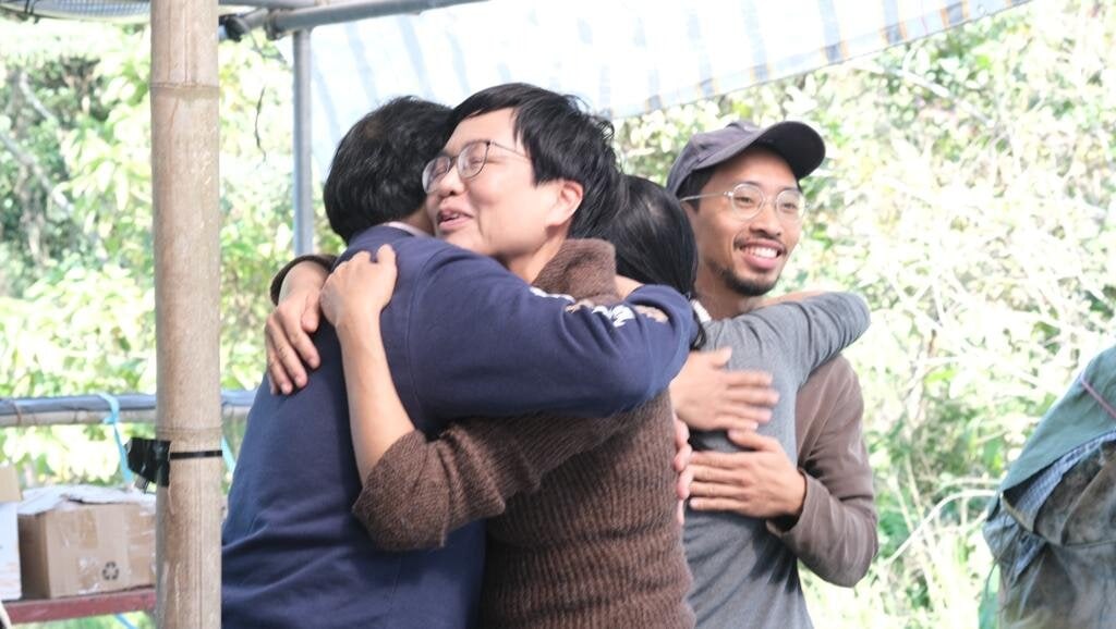 Group of diverse people embracing in an outdoor setting, smiling and connecting.