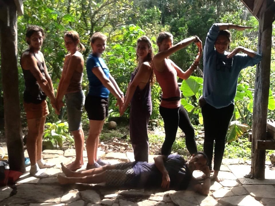Group of people in a line with varied poses in a tropical garden.