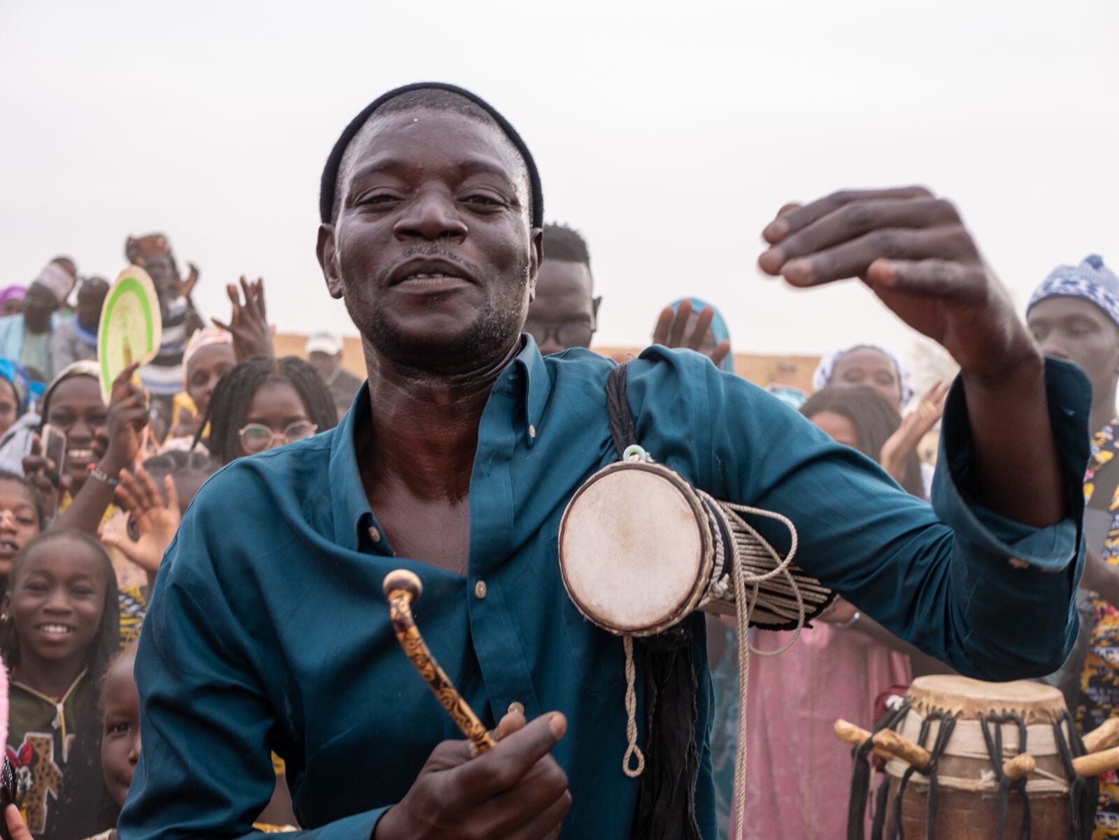 Group of joyful people at a celebration with a drummer in the foreground.