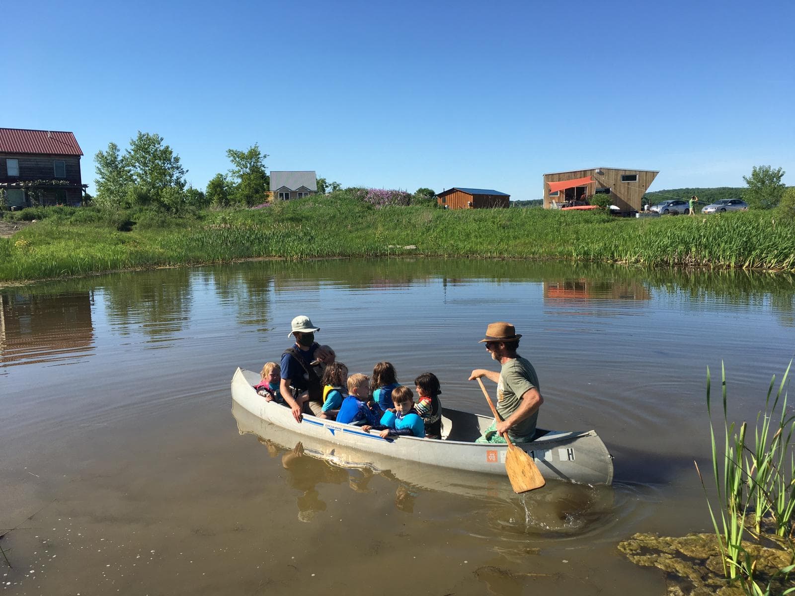 Group of people in a canoe on a calm river at an ecovillage.