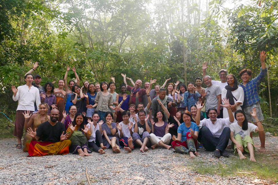 Group photo of Gaia Ashram participants smiling in a forest setting.