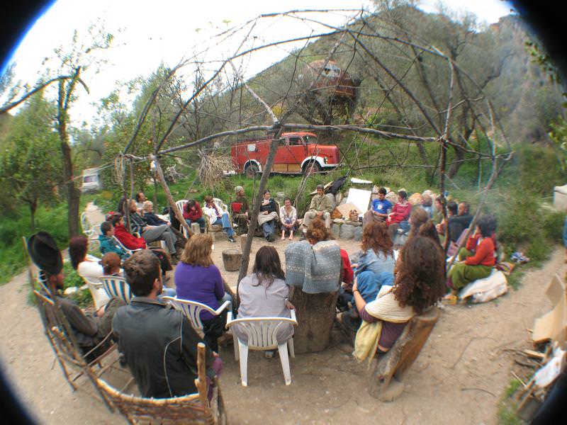 Group of people in an outdoor circle under a dome-like structure at an ecovillage event.