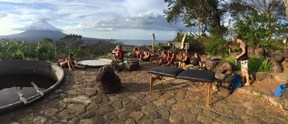 Group of people in outdoor setting at an ecovillage, with spa tubs and seating.