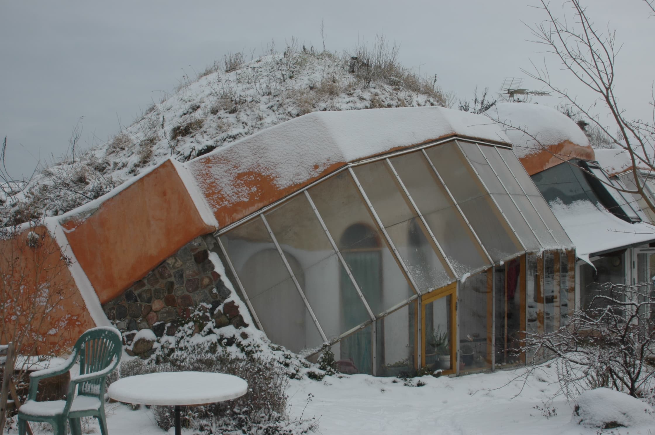 Dyssekilde Eco Village with glass greenhouse and snow.