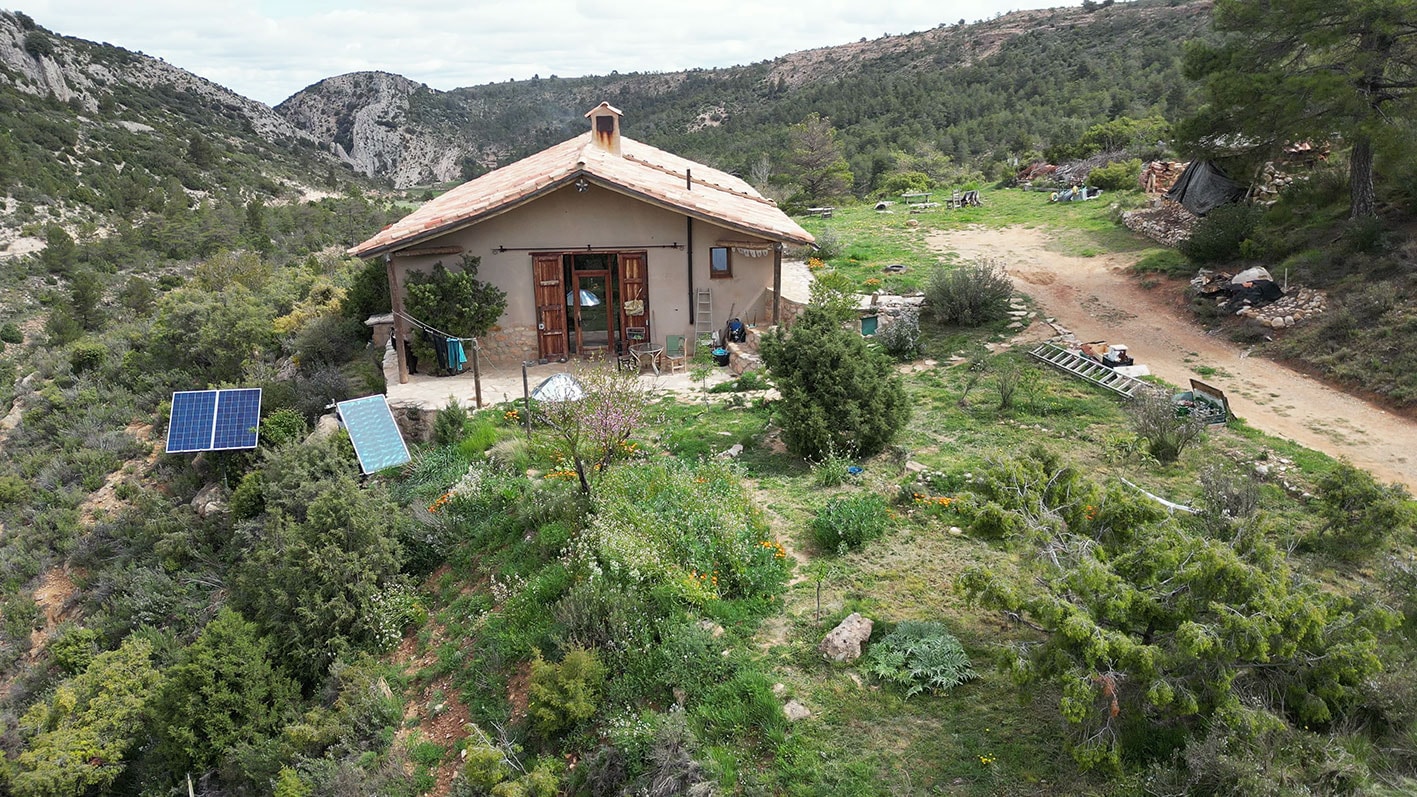 Scenic earth-sheltered cabin in a hillside eco-village with solar panels and plants.