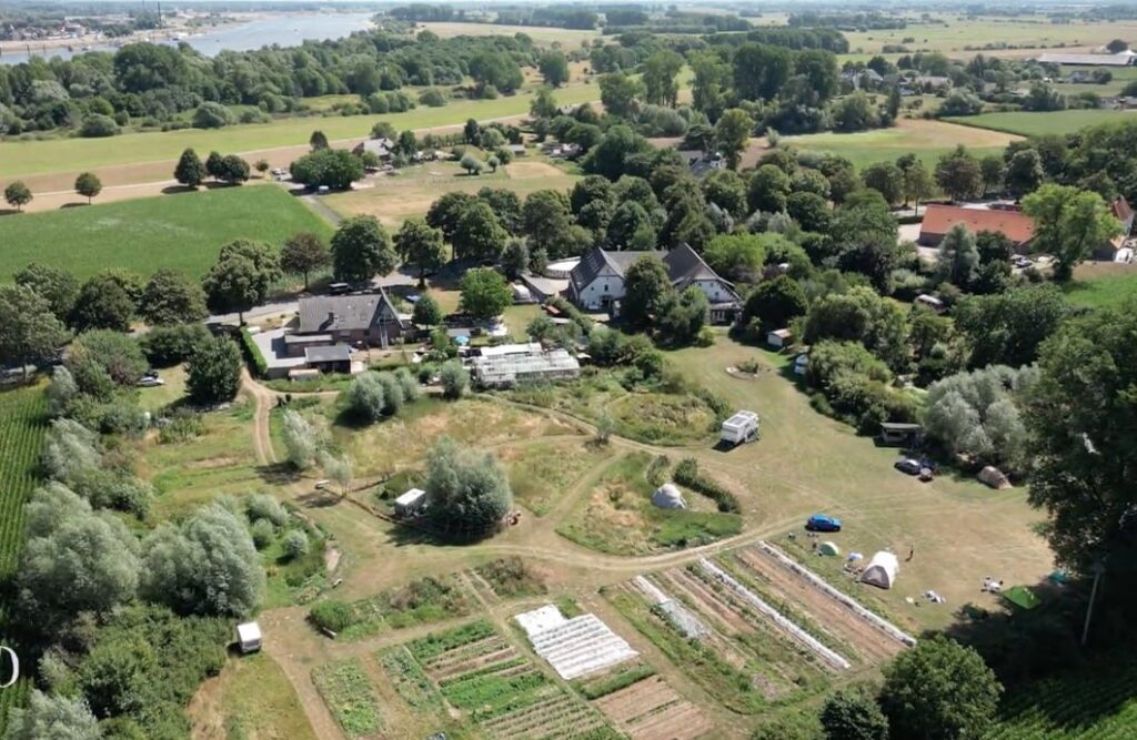 Aerial view of a biodiverse ecovillage with gardens, greenhouses and communal buildings.