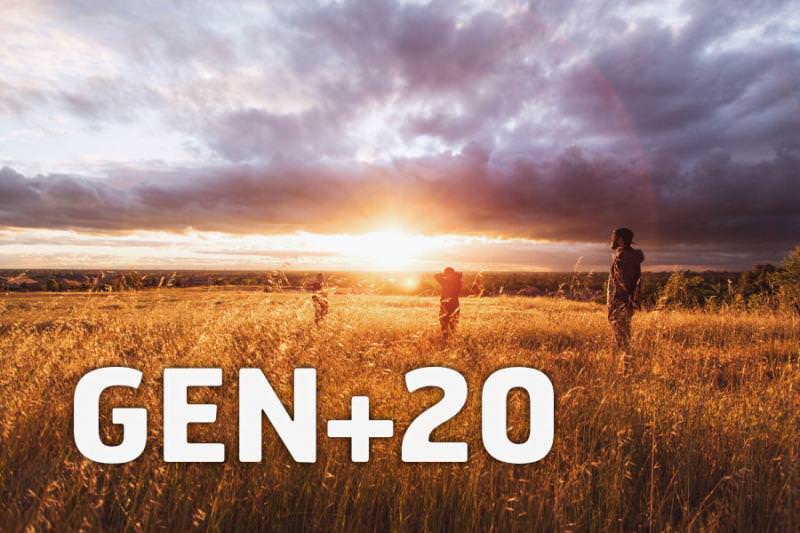 GEN+20 summit participants in a golden field at sunset.