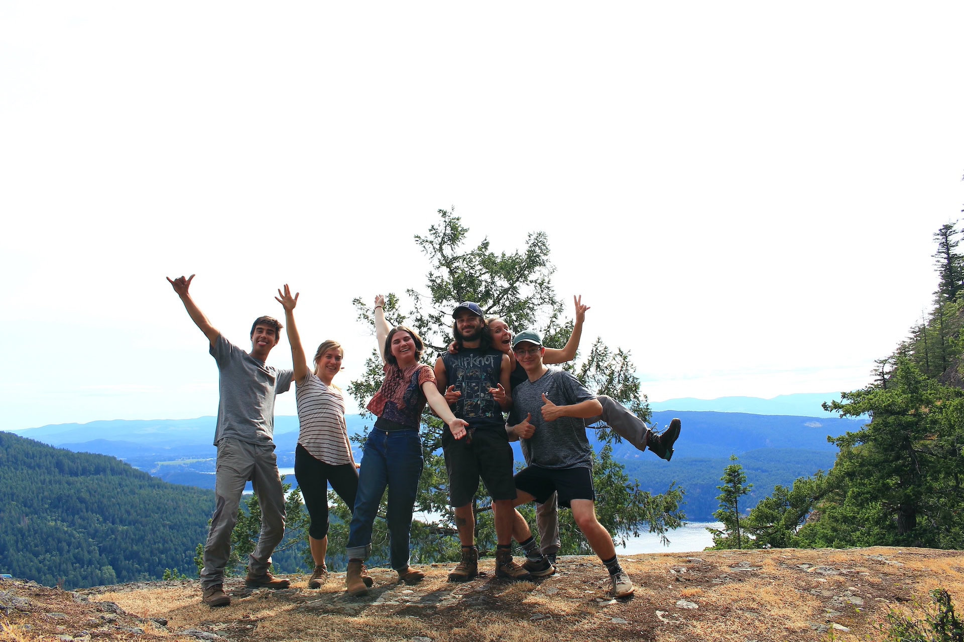 Group of hikers on a rocky overlook with forested hills in the background.